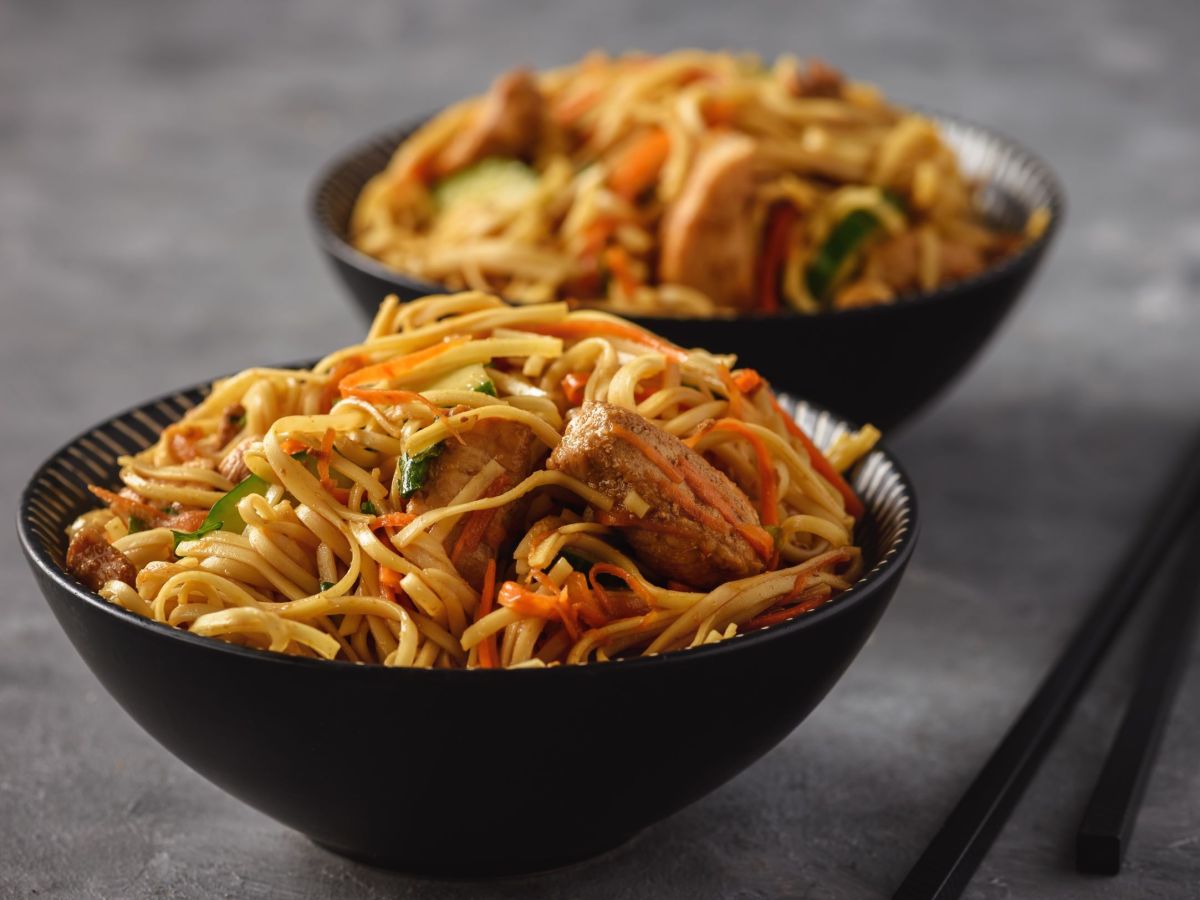 Dos tazones con fideos salteados sobre fondo oscuro