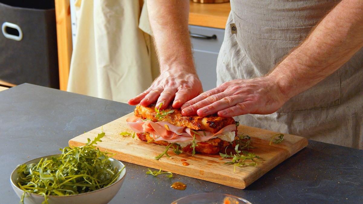 Un cocinero presenta un pan de pizza relleno cortado.