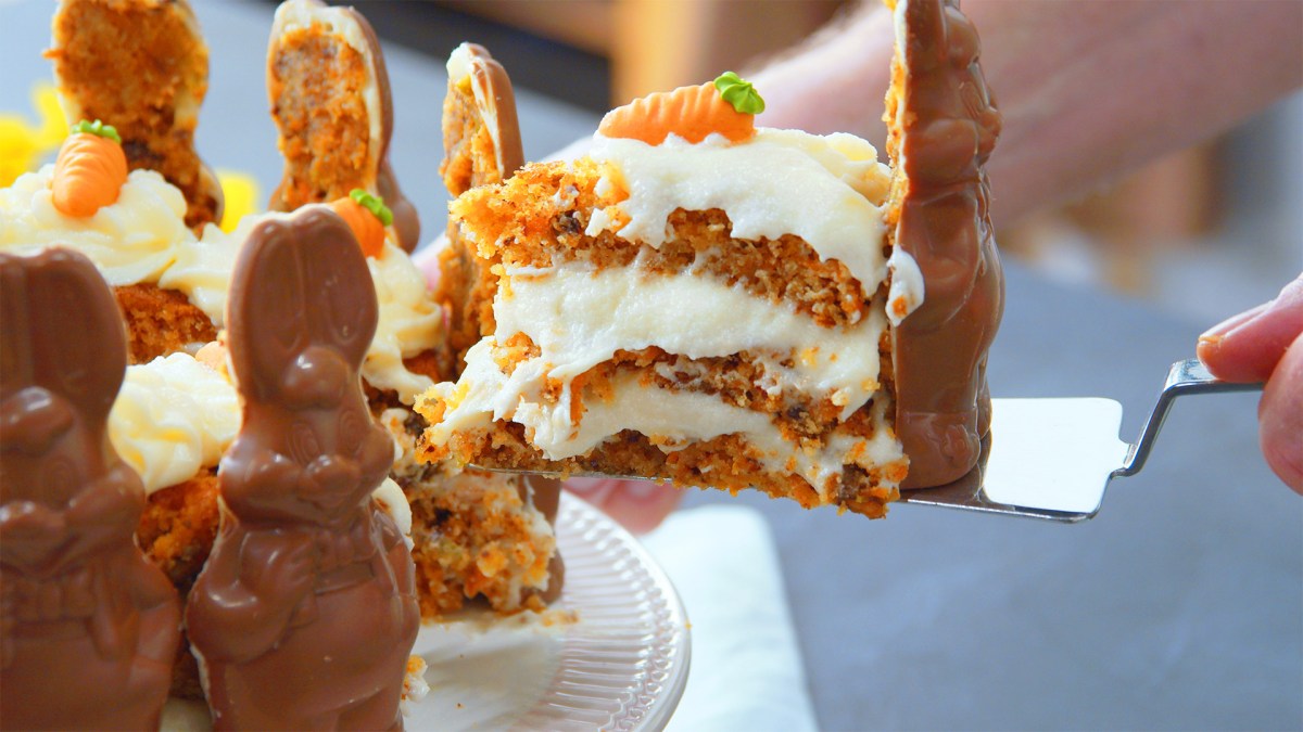 Un cocinero toma un trozo de tarta de conejito de Pascua con conejitos de chocolate.