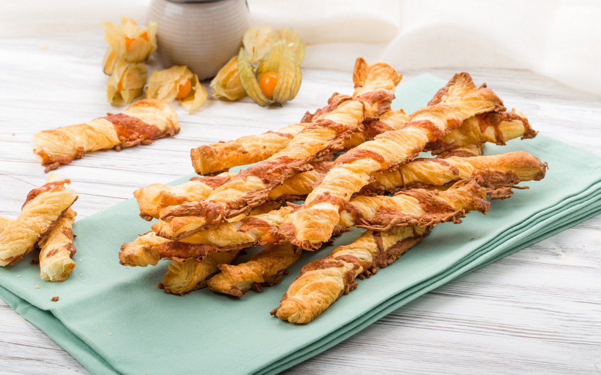 Varios palitos de queso hojaldrados sobre una servilleta azul.