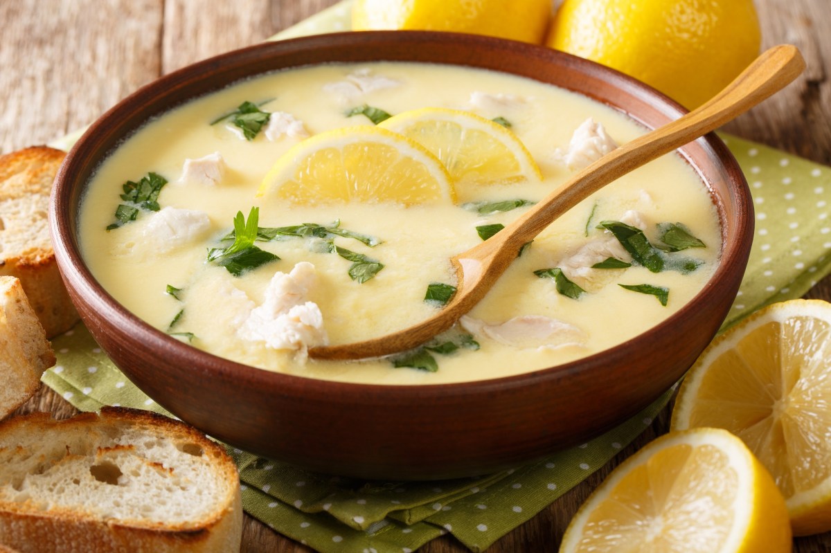 Un tazón con sopa de limón amarilla, una cuchara y rodajas de limón como decoración