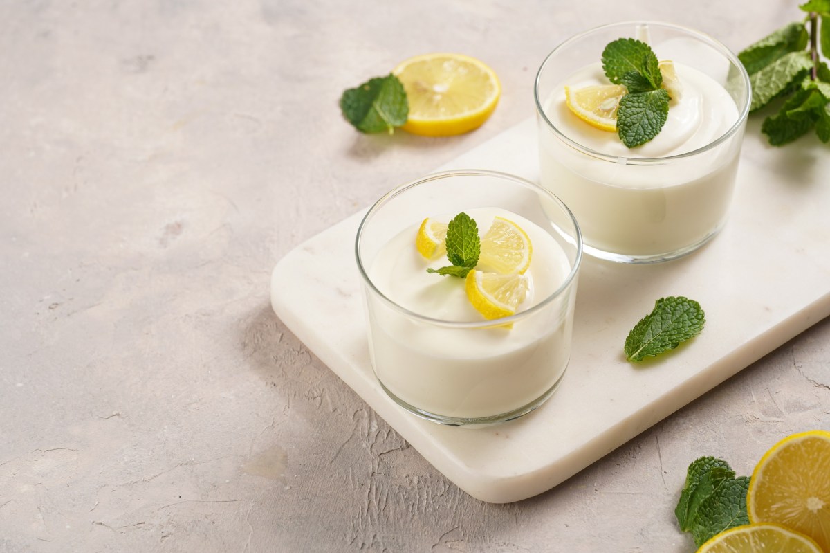 dos vasos de Syllabub, crema de limón inglesa, decorados con gajos de limón y menta, en una bandeja