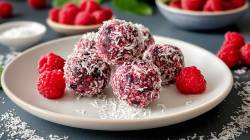 Plato con bolitas energéticas de coco y frambuesa y frambuesas frescas