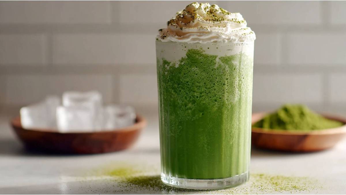 Vaso de frappuccino de matcha sobre una mesa, tazón de cubos de hielo al lado