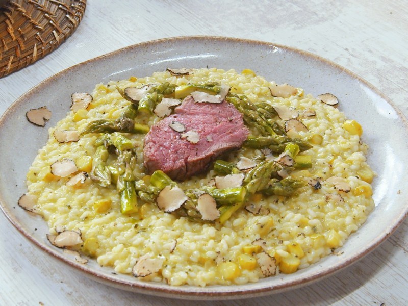 Risotto de espárragos con filete de res en un plato.