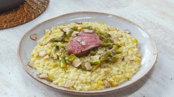 Risotto de espárragos con filete de res en un plato.