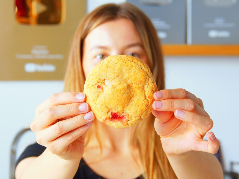 Galletas de Cheesecake con Fresas Rellenas: Una cocinera sostiene una galleta hacia la cámara.