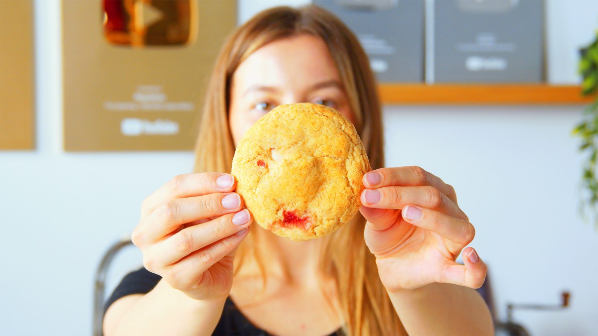 Galletas de Cheesecake con Fresas Rellenas: Una cocinera sostiene una galleta hacia la cámara.