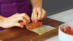 Cocinera enrolla el relleno de carne molida en una hoja de repollo blanqueada.