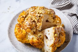 Coliflor entera al horno, cortada, en un plato.