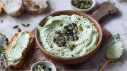 Tazón con crema para untar de semillas de calabaza y requesón, y pan al lado