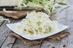 Ensalada de col en un plato cuadrado sobre una servilleta de tela gris.