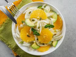 Ensalada de hinojo con aderezo de expreso, bellamente presentada en un plato. Los cubiertos están al lado.