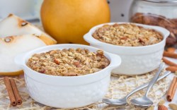 Dos pequeños moldes con gachas de avena al horno. Al fondo hay peras frescas.