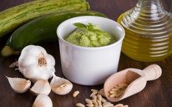 Un plato con pesto de calabacín. Alrededor, ingredientes frescos.
