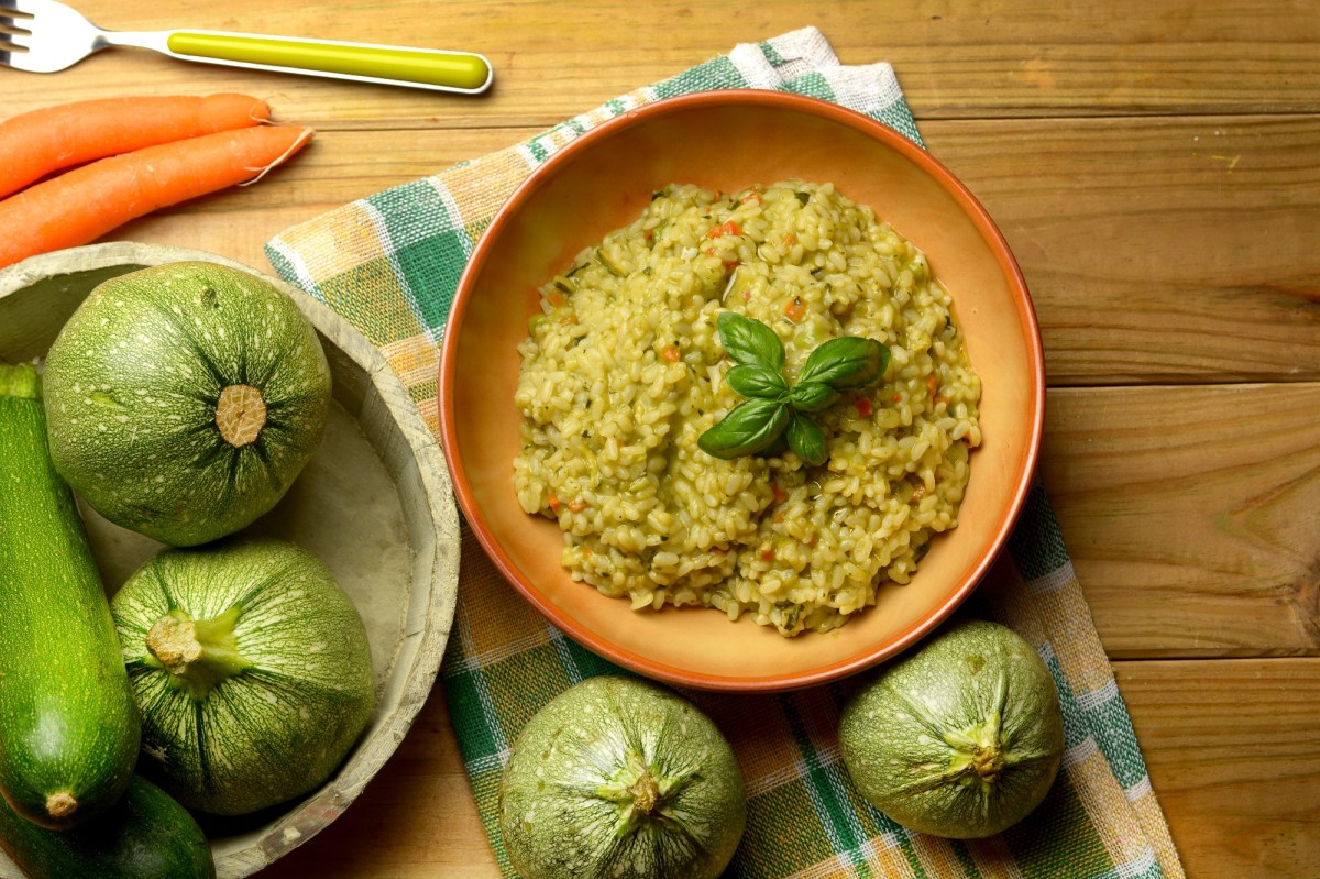 Un plato de risotto de calabacín sobre una mesa decorada.