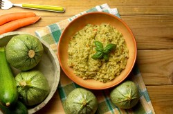 Un plato de risotto de calabacín sobre una mesa decorada.