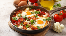 Una sartén con shakshuka de coliflor sobre una tabla.